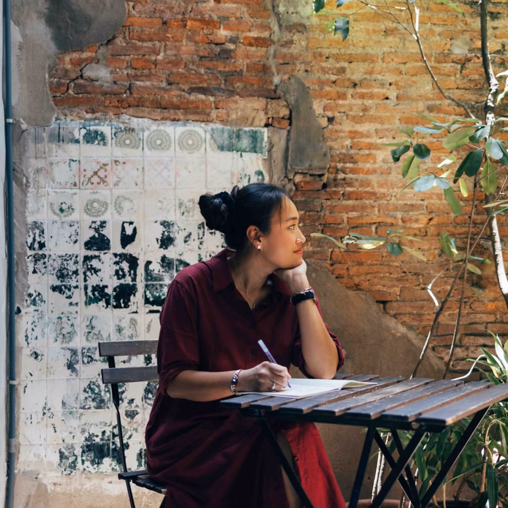 Person sitting at a table writing on paper